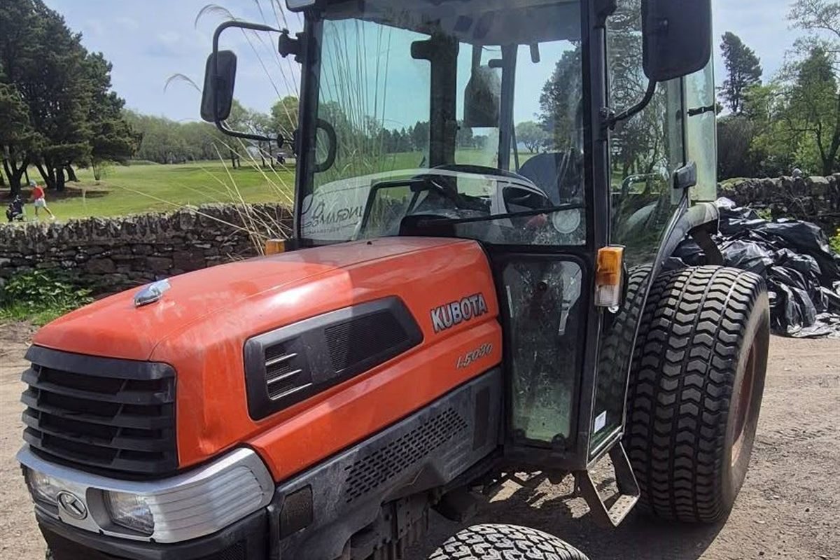 A Kubota L5030 compact tractor at the edge of a golf course
